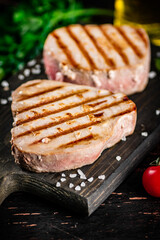 Grilled tuna on a cutting board with parsley and tomatoes. 