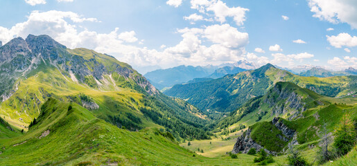 Panoramic landscape typical of the Alps with beautiful green meadows, mountains and valleys on a nice sunny day . Popular travel destination. Summer tourism. Italian Alps, Dolomites, Italy.
