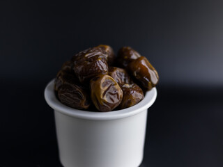 fresh dates on white bowl, black background