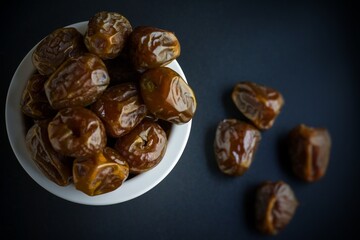 fresh dates on white bowl, black background