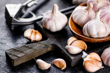 Garlic on a wooden plate on a cutting board. 