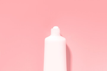 Empty mockup white tube with cream or lotion on a pink background.