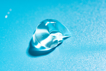 Liquid cosmetic gel drop, hyaluronic acid gel on a blue background.