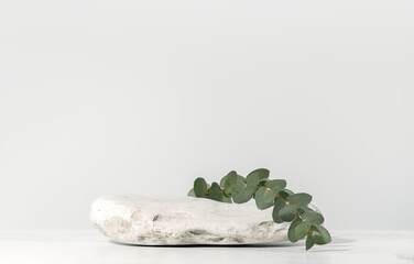 Beauty cosmetic product presentation scene made with white stone and eucalyptus branch on white...
