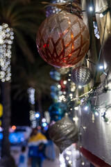 Close up of a Christmas bulb ornament and lights at night outside, in selective focus, useful for backgrounds