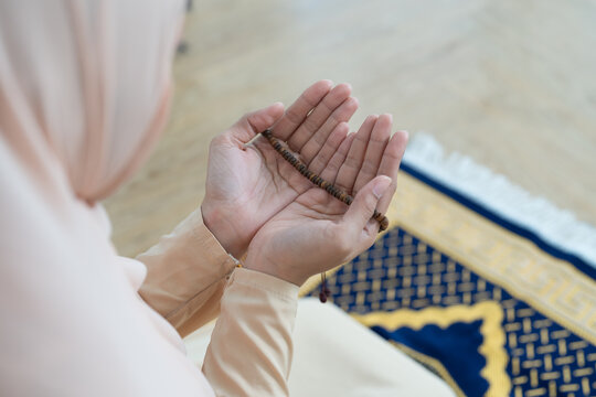 Asian young Muslim woman wear hijab headscarf and hijab dress sitting and praying and holding prayer beads