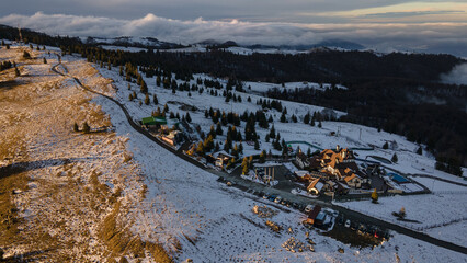 Aerial view of a small resort on top of the mountain in winter season at sunset. Photography was shot from a drone at a higher altitude. Aerial view of a resort in winter at sunset