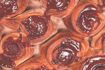 Homemade cinnamon buns with spices and caramel on parchment paper.