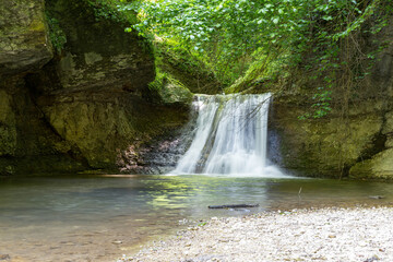 Summer, mountainous terrain, hiking trails running through the park, with a view of the waterfall and places for walking and relaxing.