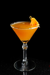 Orange cocktail with mandarins in martini glass on black background.