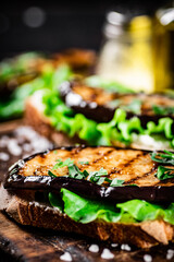 A fragrant sandwich with grilled eggplant on a cutting board. 