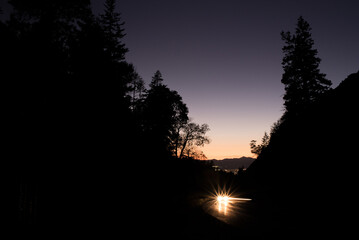 Sunset in canyon with car driving on the road and trees silhouette