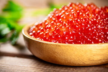 Red caviar in a plate on the table with parsley. 