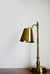 Brass gold desk lamp in background of white wall