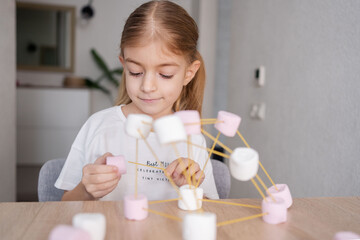 Child girl make chemistry science molecular model at home. 