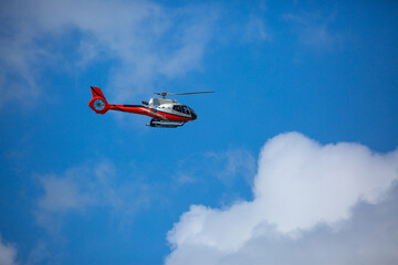 Fototapeta na wymiar Rescue helicopter flies in the sky among the clouds. Red-white Helicopter.