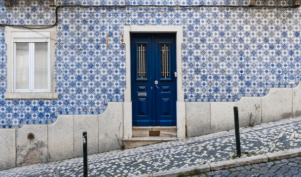Building facade with typical tiles from Lisbon, Portugal, in a hilly street.