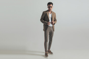 sexy man with dark hair wearing plaid pants and adjusting jacket