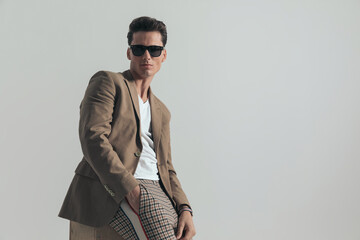 handsome fashion man with beige jacket and sunglasses posing