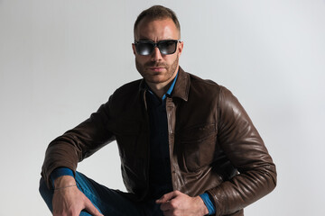 Obraz premium confident unshaved man wearing brown leather jacket and sunglasses