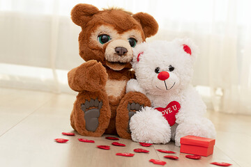 Valentine's Day concept. Two cute teddy bears brown and white are sitting on the floor with red hearts.