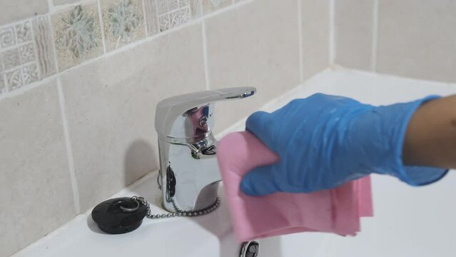 4k v&iacute;deo. Mujer de la limpieza secando con una bayeta el grifo del cuarto de ba&ntilde;o