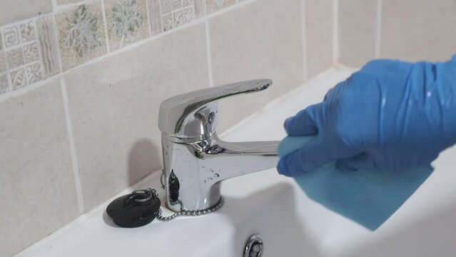 4k v&iacute;deo. Mujer de la limpieza secando con una bayeta el grifo del cuarto de ba&ntilde;o