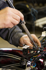 Electrician soldering electrical wires to electrical equipment.