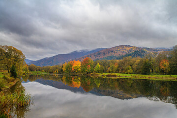 Autumn landscape - view of the lake with the reflection of autumn trees in the Carpathian mountains, Ukraine