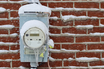 Electricity meter outside a building in winter, with snow and ice