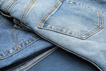 Lots of jeans pants in a stack. Denim background.