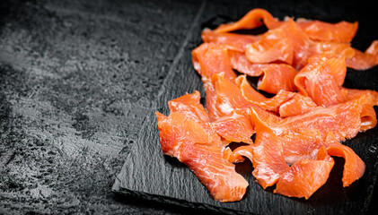 Pieces of salted salmon on a stone board. 