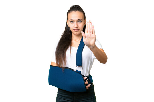 Young Arabian woman with broken arm and wearing a sling over isolated chroma key background making stop gesture
