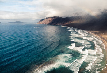 Aerial view by drone of yellow sand Famara beach with ocean and waves. Beach with a big waves and...