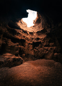 A view of the inside of Cave with beautiful natural sunlight from the  top throught the hole. Moody and dark empty cave with soft light.