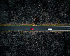 Road with two cars with motion blur from above by drone - night time photo in Lanzarote. Straight road among the lavas on the sides in Canary Islands - dark moody shot.