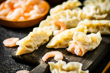 Gyoza dumplings with shrimp on a cutting board. 