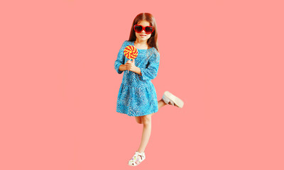 Portrait of beautiful little girl child wearing blue dress on pink background