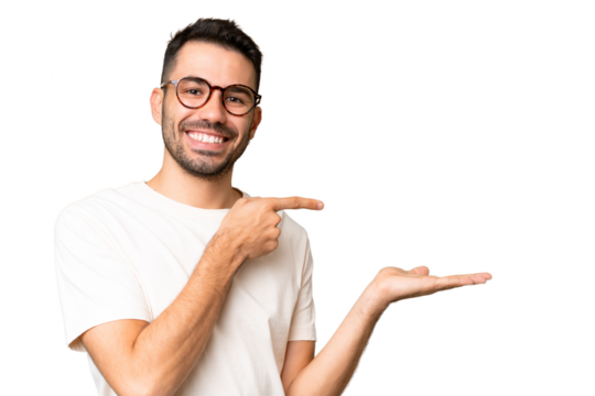 Young handsome caucasian man over isolated chroma key background holding copyspace imaginary on the palm to insert an ad