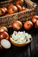 Pieces of onion in a plate and whole onions in a box. 