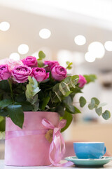 a bouquet of flowers on the table and a cup of coffee