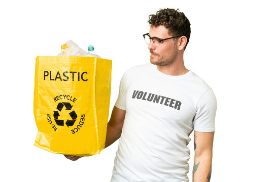 Brazilian man holding a bag full of plastic bottles to recycle over isolated chroma key background with happy expression