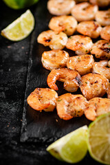 Grilled shrimp on a stone board with pieces of lime. 