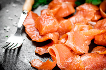 Pieces of salted salmon with greenery on a stone board. 