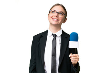 Young TV presenter caucasian woman  over isolated background looking up while smiling