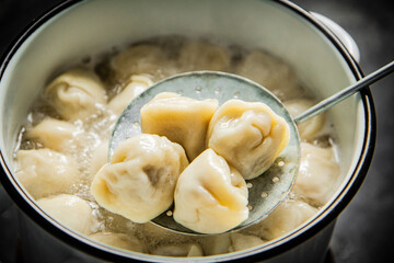 Dumplings are taken out of the pan with a skimmer. 