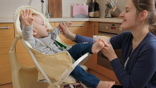 Little baby boy refusing eating in highchair and being naughty. Concept of parenting, healthy nutrition and baby feeding
