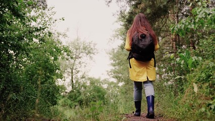 Woman on vacation walking alone in forest, meditation. Hiking woman tourist in forest in rain. Free tourist girl walking with backpack through dense forest nature on summer day. Free travel concept.