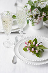 Beautiful table decor for a wedding dinner with a spring blooming apple tree flowers. Celebration of a special event. Fancy white plates, wineglasses