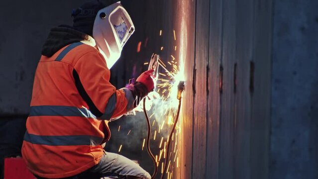 Skilled Construction Site Contractor Worker in Protective Wear Operating Electric Arc Welder